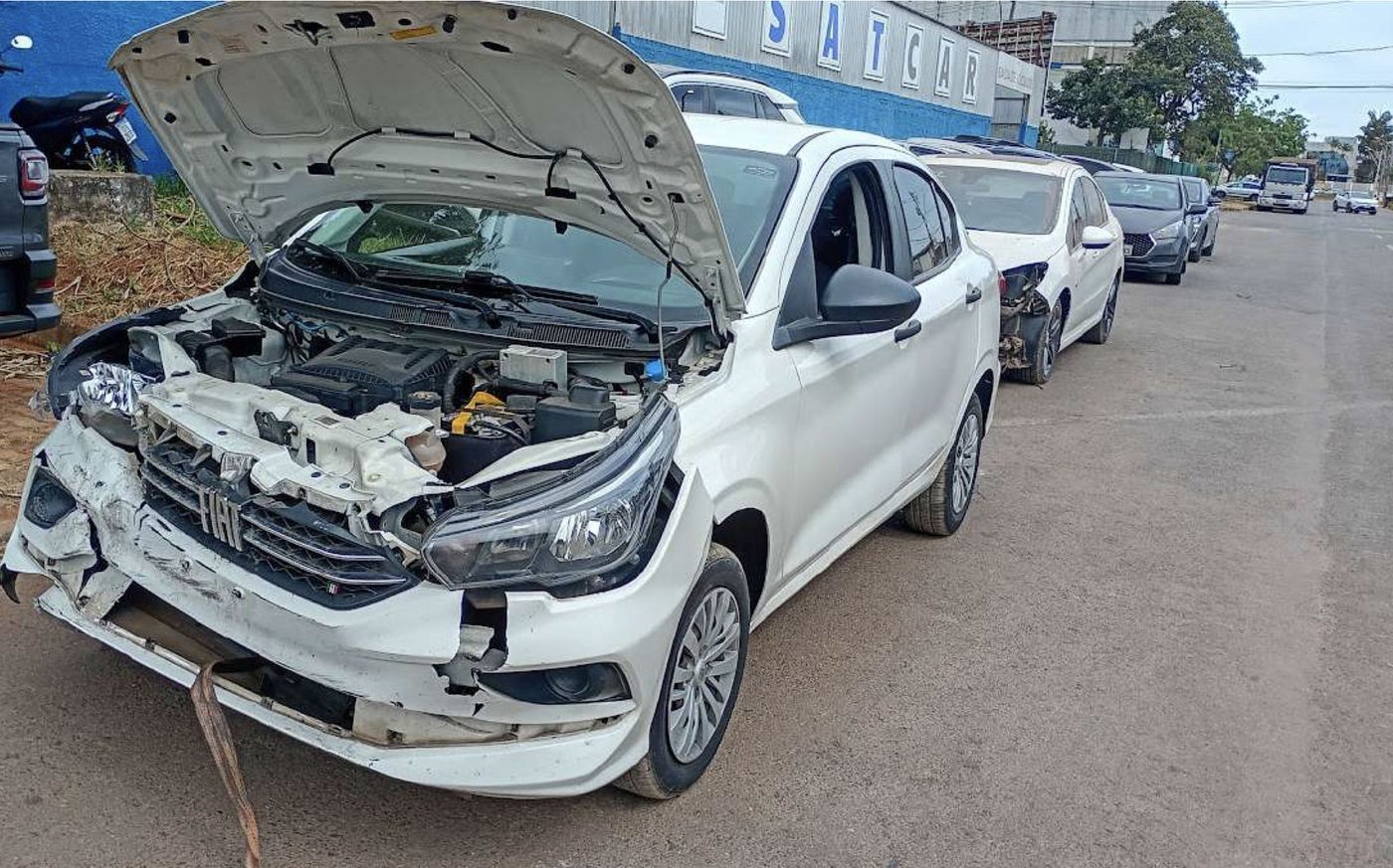 Carro branco com a frente danificada após colisão